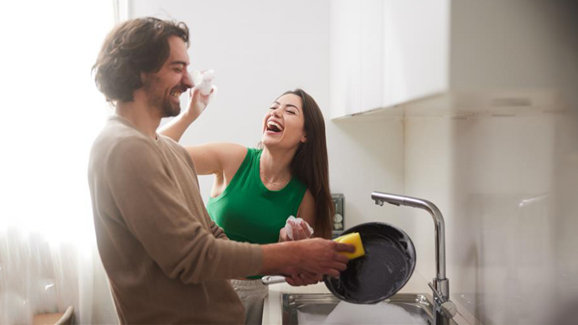 Paar lachend beim Abspülen mit Schwamm